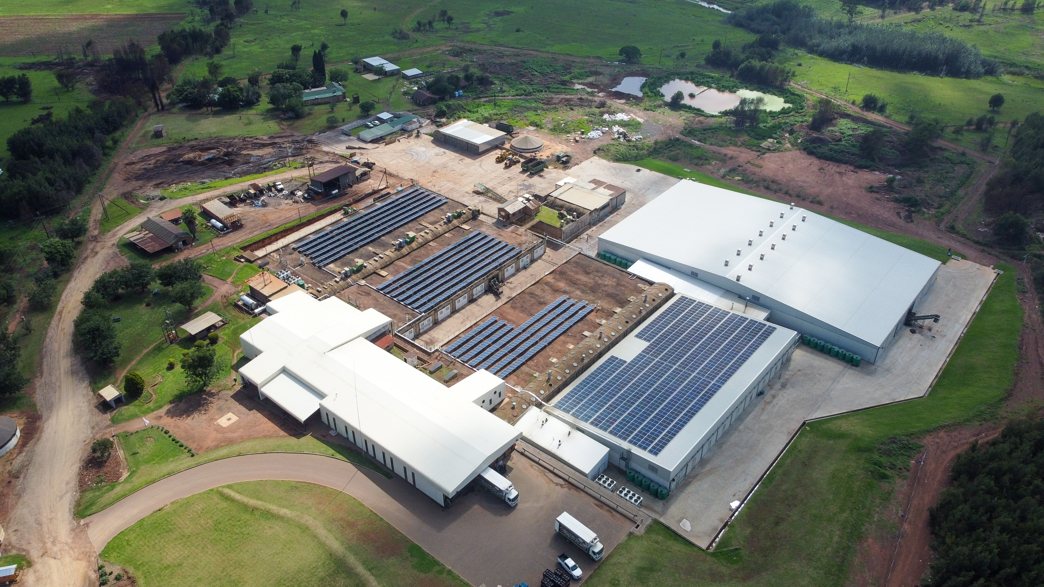 Aerial view of an agri-processing facility with growing tunnels and adjacent solar arrays