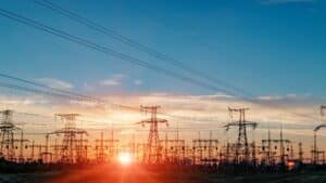 Electricity transmission towers and power lines silhouetted against a sunset sky, representing South Africa's evolving wholesale electricity market and the shift towards competitive energy trading under SAWEM